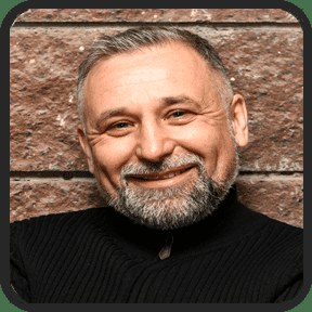 Smiling bearded man in front of a brick wall